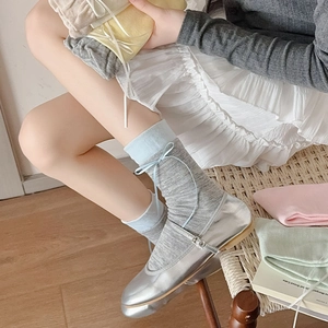 Dettaglio di calze grigie in maglia con fiocco blu e scarpe Mary Jane color argento
