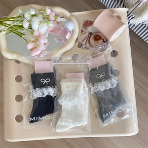 Detail of lace trim socks with pearl bows in black white and gray on a tray