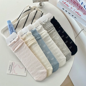 Detail of multi-color ruffled socks with bow-knot jacquard patterns in a white tray