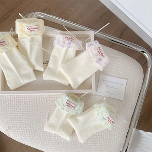 Détail de chaussettes mi-hautes crème avec revers à carreaux et nœuds en ruban doux