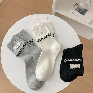 Gros plan de chaussettes en coton avec bords ondulés et étiquettes en trois couleurs