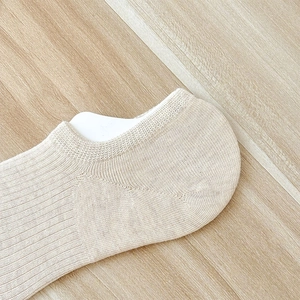 Detail der beige Füßlinge mit vertikalem Rippenstrickmuster auf natürlichem Holzhintergrund