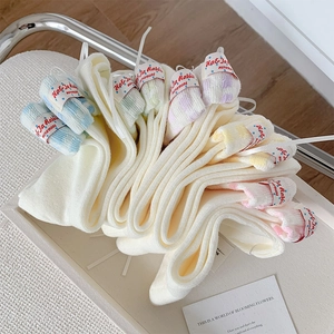 Détail de chaussettes mi-mollet blanc crème avec revers à carreaux pastel et rubans