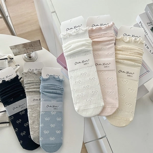 Detailed view of ruffle edge socks with knitted bow patterns and elegant scalloped cuffs