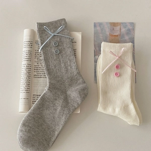Detail of grey and beige cotton ribbed socks with blue ribbon bows and vintage buttons