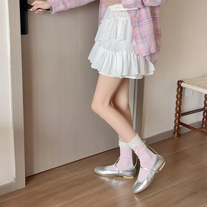 Dettaglio di scarpe Mary Jane argento con calze rosa e gonna a balze bianca a strati