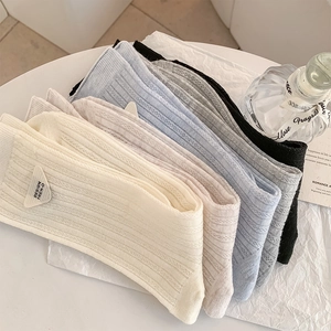Close-up of ribbed knit socks with triangular logo label in various pastel colors