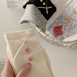 Detail of sweet ribbon bow and decorative buttons on ribbed knit crew socks