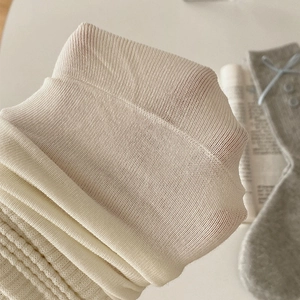 Detailed macro view of cream-colored ribbed knit fabric texture and soft cotton material