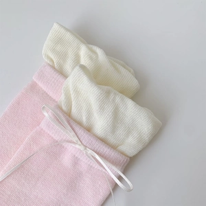 Dettaglio di calze in maglia con fiocchi in nastro rosa e bianco crema