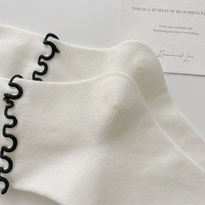 Détail de chaussettes en tricot blanc avec bords ondulés noirs et carte décor