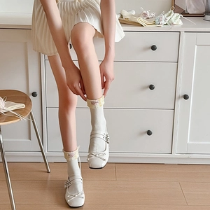 Détail de chaussettes blanches avec bordure florale jaune et nœuds en ruban élégants