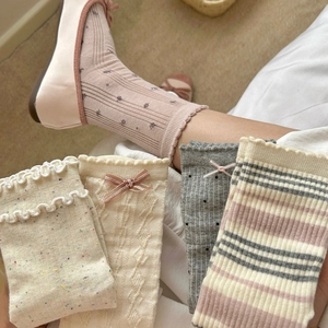Détail de chaussettes en tricot avec nœud doux, bords volantés et motifs vintage
