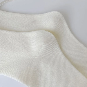 Dettaglio del tallone rinforzato e della trama a maglia fine dei calzini bianco crema