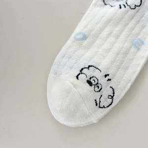 Macro detail of white ribbed knit socks featuring blue letters and cute cartoon dog graphics