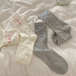 Detail of knit crew socks featuring delicate ribbon bows and small decorative buttons