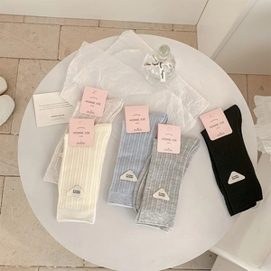 Detail of knitted ribbed socks in assorted pastel colors with triangular fashion labels