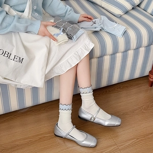 Close-up of cute bow socks with ruffled edges styled with silver Mary Jane shoes