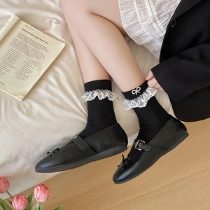 Detail of lace trim socks with pearl bow decoration and black Mary Jane shoes