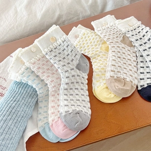 Detail of colorful lattice knit socks with delicate button accents and ruffled edges