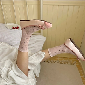 Gros plan de ballerines roses à nœud avec des chaussettes en maille fleurie dans une chambre