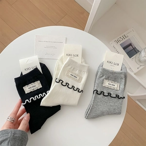 Détail de trois paires de chaussettes en coton avec bords dentelés et étiquettes