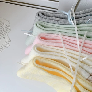 Dettaglio calzini a coste color Morandi legati con eleganti nastri decorativi bianchi