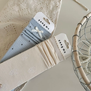 Detail of knit socks with black polka dots, white silk bows and floral lace patterns