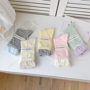 Primo piano di cinque paia di calze in maglia color pastello con confezione regalo nastro