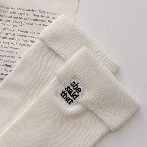 Close-up of white ribbed knit socks featuring a folded cuff and embroidered logo label