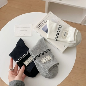 Trois paires de chaussettes en coton avec bords à volants et étiquettes en noir blanc gris