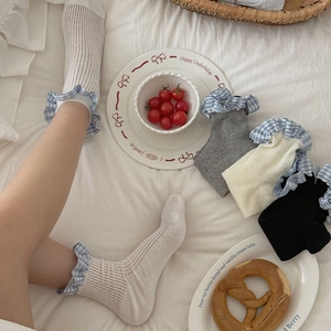 Detail of knit crew socks with blue gingham ruffled cuffs in white, gray and black colors