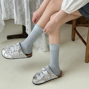 Close-up of light blue ruffle socks with pink bow patterns paired with silver shoes