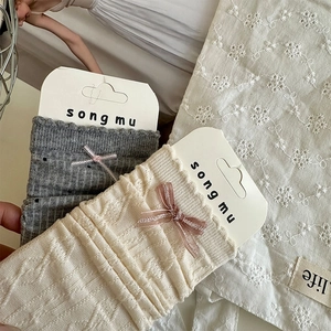 Détails de chaussettes en coton côtelé gris et beige avec nœuds délicats et emballage