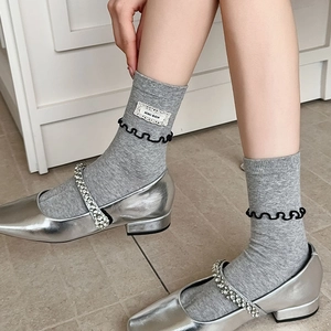 Détail de chaussettes en coton gris avec bords ondulés et étiquette en dentelle