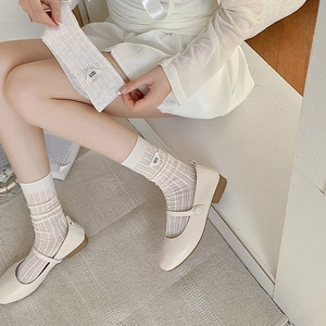 Detail of white ribbed cotton socks with triangle logo tag paired with Mary Jane shoes