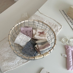 Détail de cinq paires de chaussettes en coton avec volants et nœuds dans un panier