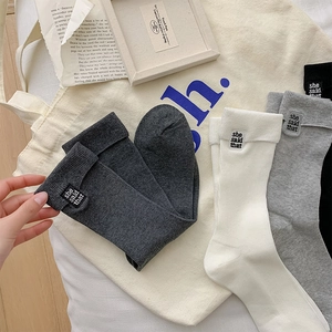 Detail of cotton crew socks featuring rolled cuffs and she said that letter embroidery