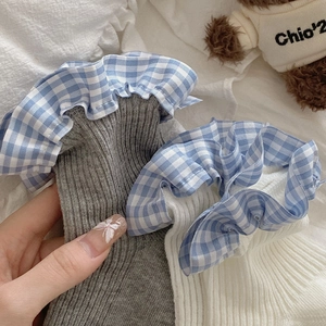 Detailed knit texture of white and grey socks with blue checkered ruffle lace edges