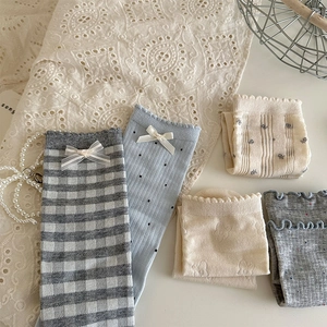Detail of cotton socks featuring polka dots, floral patterns, and delicate bow decorations