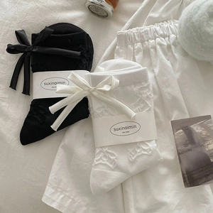 Detail of bear embroidery and satin bow on black and white crew socks with packaging