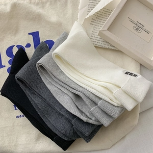 Detail of four crew socks in black, grey and white with minimalist letter patches