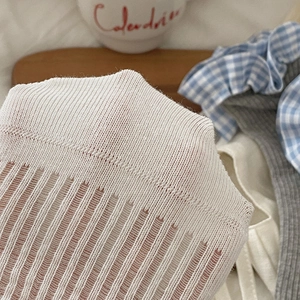 Close-up of white ribbed knit fabric showing breathable texture and elastic mesh detail