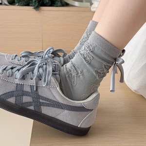 Detail of grey bear embossed mid-calf socks with 3D bow and premium suede sneakers