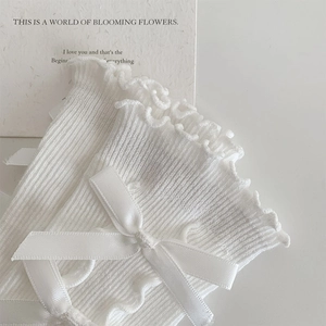Close-up of white ballet style socks with ruffle edges and satin bow details