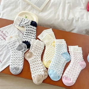 Detail of knit crew socks with hollow grid pattern and colorful contrast trim and button