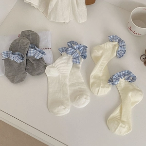 Detail of blue plaid ruffled cuffs on rib-knit cotton socks in white and grey colors