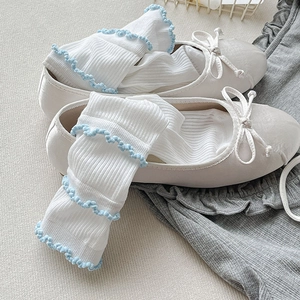 Détail de chaussettes à volants blanc et bleu avec ballerines crème élégantes