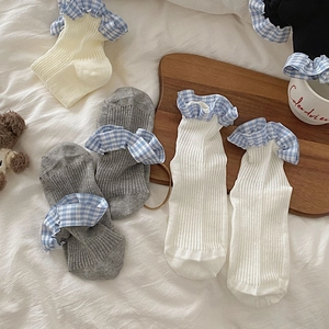 Detail of ribbed knit crew socks featuring blue gingham ruffle cuffs on a soft background