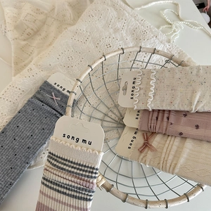 Détail de chaussettes en coton avec nœuds et volants dans un panier décoratif